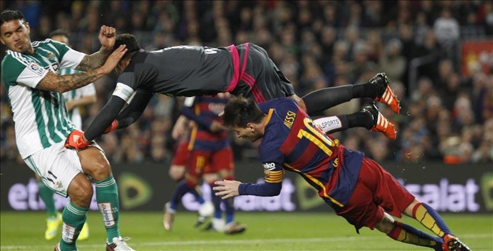 El portero del Real Betis Balompié Adán despeja (i) un balón ante la presencia del delantero argentino del FC Barcelona Leo Messi (d), en la jugada que supuso el penalti a favor del equipo azulgrana. EFE
