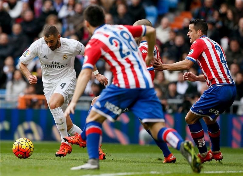 El delantero del Real Madrid Karim Benzema (i) disputa un balón con los jugadores del Sporting de Gijón durante el partido de la vigésima jornada de liga en Primera División, disputado en el estadio Santiago Bernabéu. EFE