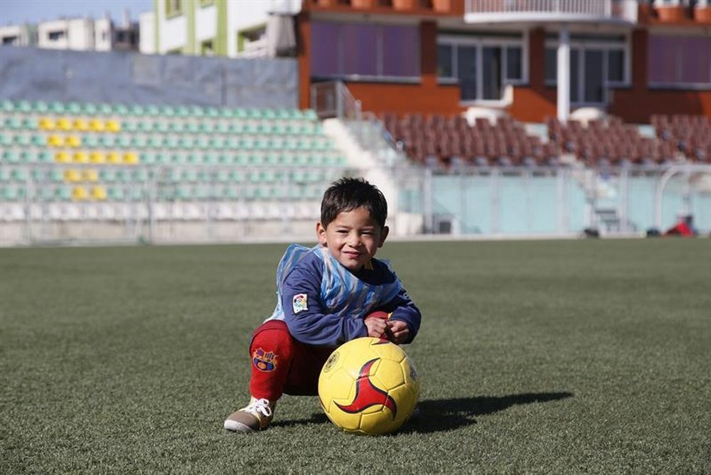 El niño afgano de 5 años Murtaza Ahmadi posa con una camiseta de su ídolo, el delantero argentino Lionel Messi, hecha con una bolsa de plástico, en un campo de fútbol de Kabul, Afganistán. EFE