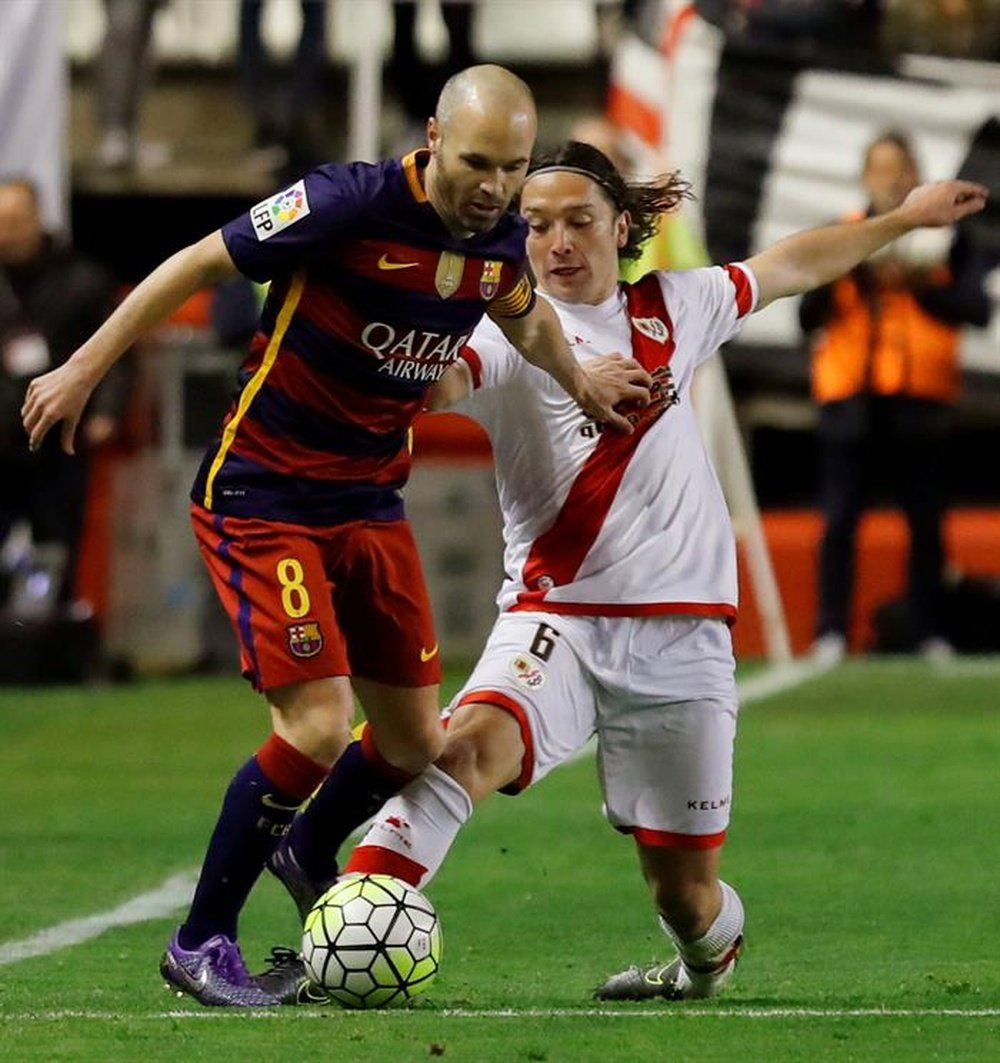 El centrocampista del FC Barcelona Andrés Iniesta (i) disputa un balón con el centrocampista chileno Manuel Iturra (d), del Rayo Vallecano. EFE
