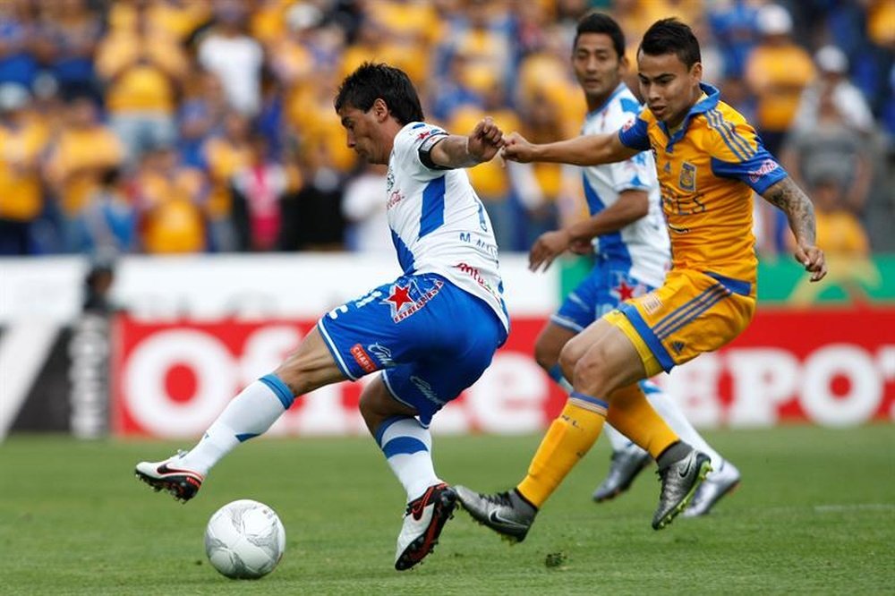 El futbolista Matías Alustiza (i), de los Tigres de la UANL, fue registrado al disputar un balón con Antonio Briseño (d), del Puebla, durante un partido de la jornada 11 del torneo Clausura del fútbol en México, en el estadio Cuauhtémoc de la ciudad de Puebla (México). EFE