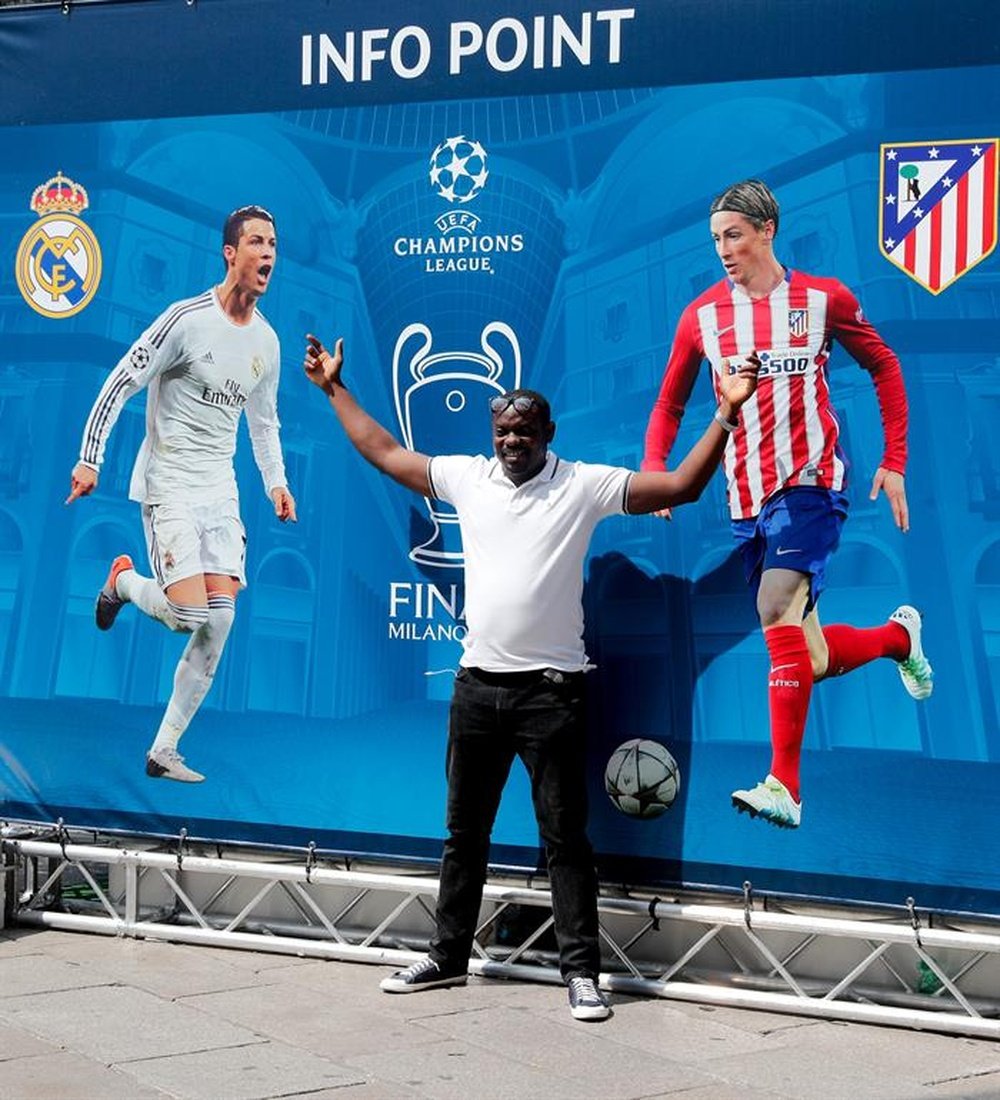 Un aficionado se fotografía hoy en la plaza del Duomo, en Milán, frente a uno de los carteles publicitarios de la final de la Liga de Campeones, que enfrentará este sábado al Real Madrid y el Atlético en el Estadio de San Siro. EFE