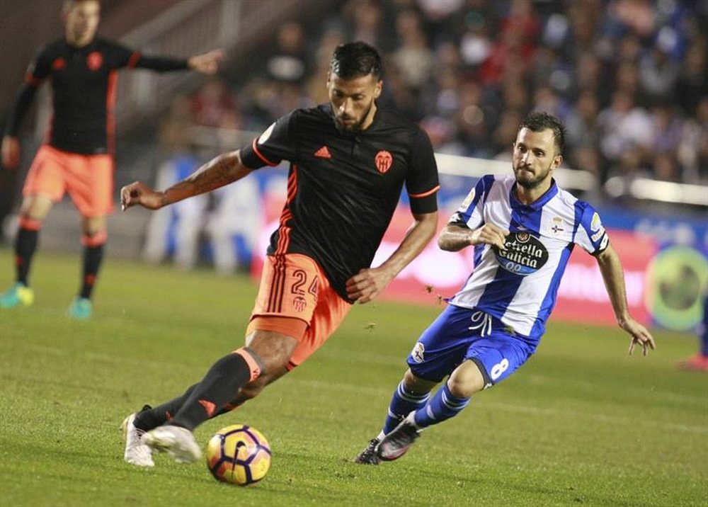 El defensa argentino del Valencia CF Ezequiel Garay (i) se escapa del turco Emre Colak, del Deportivo de La Coruña, durante el partido de la décima jornada de Liga en Primera División disputado anoche en el estadio Riazor, en A Coruña. EFE