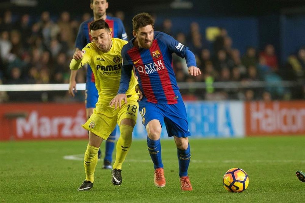El delantero argentino del F. C. Barcelona, Leo Messi (d), conduce el balón ante el delantero italiano del Villarreal, Nicola Sansone, durante el encuentro correspondiente a la decimoséptima jornada de primera división, disputado anoche en el Estadio de la Cerámica de la localidad castellonense. EFE
