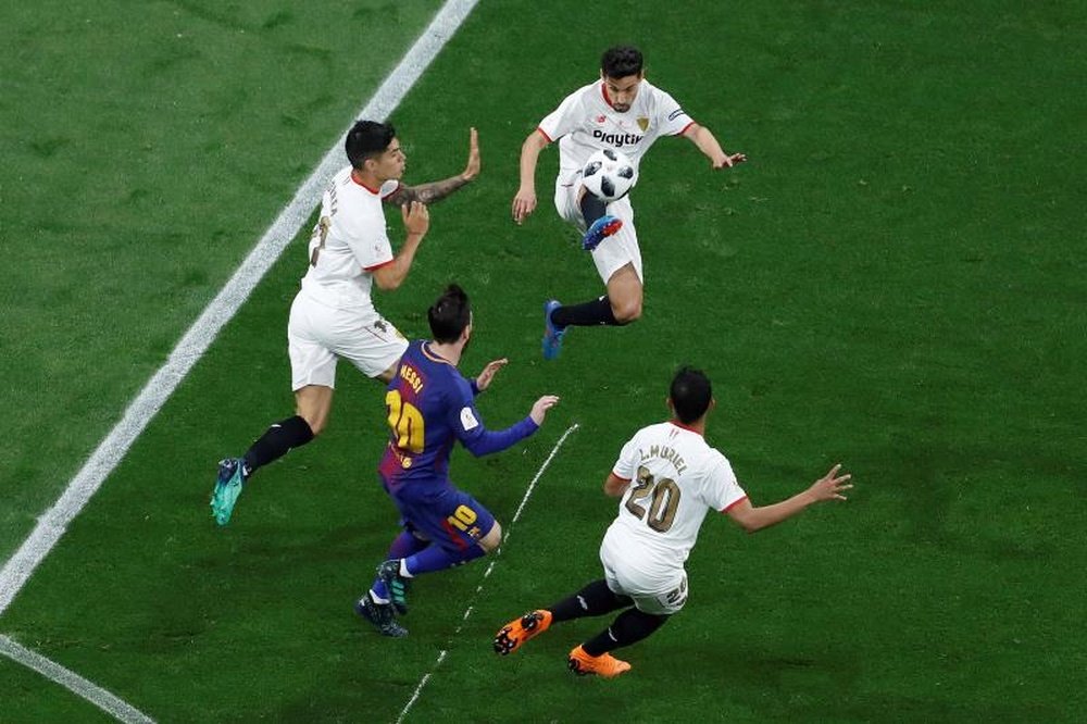 Sevilla players protect the ball from Barcelona forward Lionel Messi. EFE