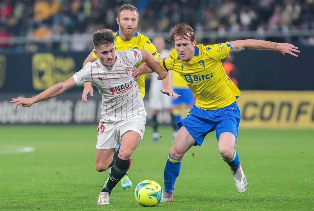 El delantero del Sevilla FC Iván Romero (i) lucha por el balón con el centrocampista del Cádiz CF Álex Fernández, durante el partido entre el Cádiz CF y el Sevilla FC. EFE/Román Ríos.