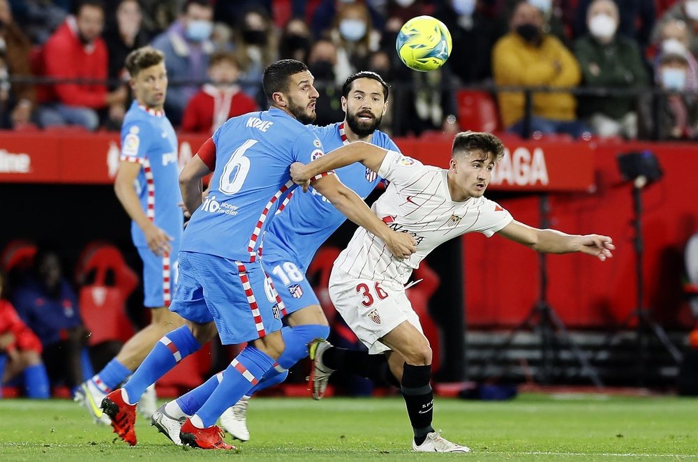 El delantero del Sevilla, Iván Romero (d), sujetado por el centrocampista del Atlético de Madrid, Koke, en el estadio Sanchez Pizjuan, en Sevilla en foto de archivo de Jose Manuel Vidal.EFE