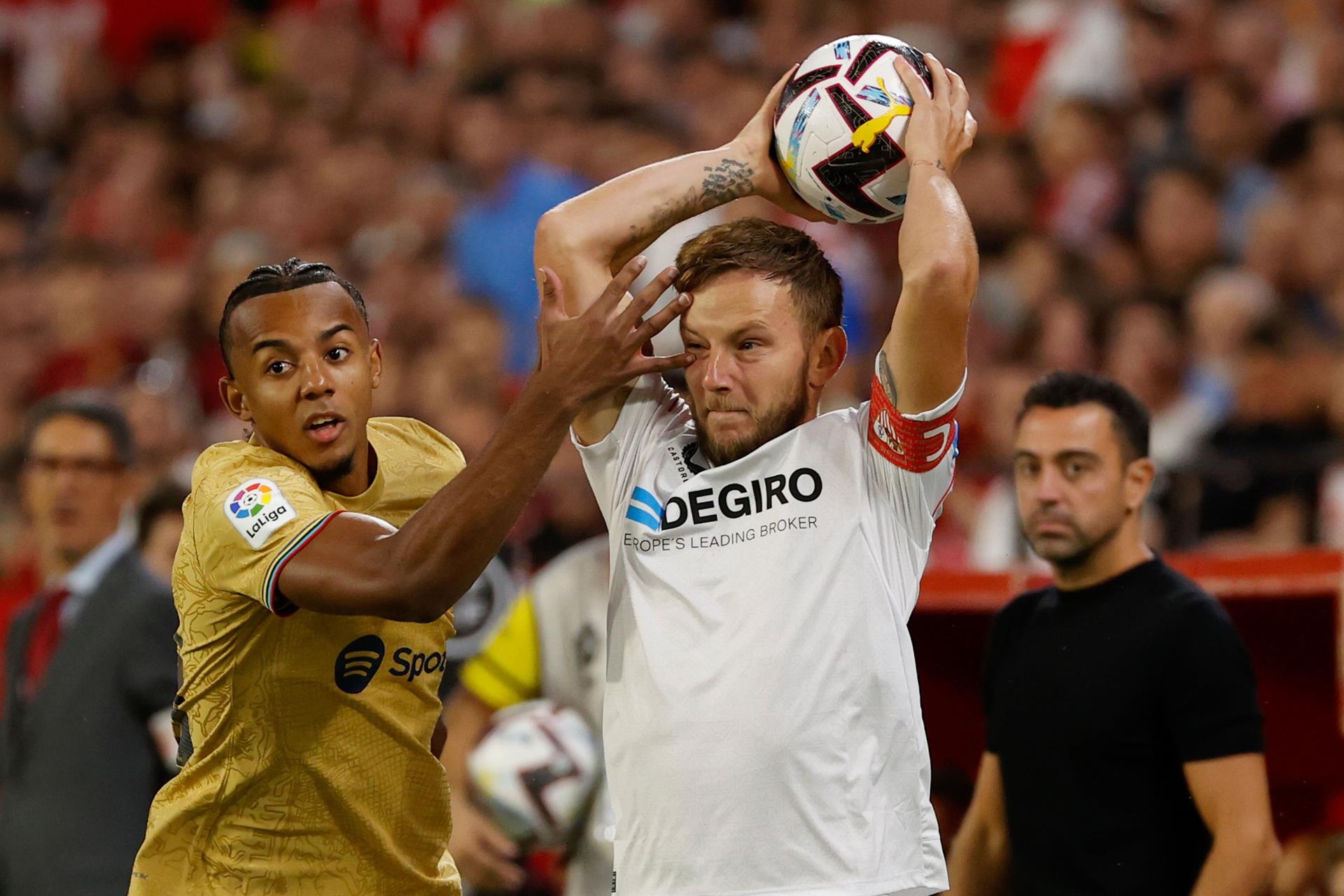 El centrocampista del Sevilla FC Iván Rakitic junto al francés Jules Koundé, del FC Barcelona, durante el partido de la cuarta jornada de LaLiga que se juega en el estadio Sánchez-Pizjuán, en Sevilla. EFE/ Julio Muñoz