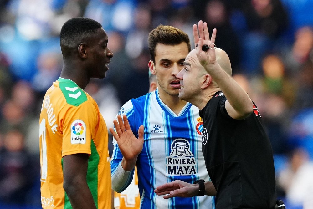 El centrocampista brasileño del Betis Luiz Henrique (i) conversa con el colegiado en un momento del partido de LaLiga que el Espanyol y el Betis disputaron en el RCDE Stadium. EFE/ Enric Fontcuberta