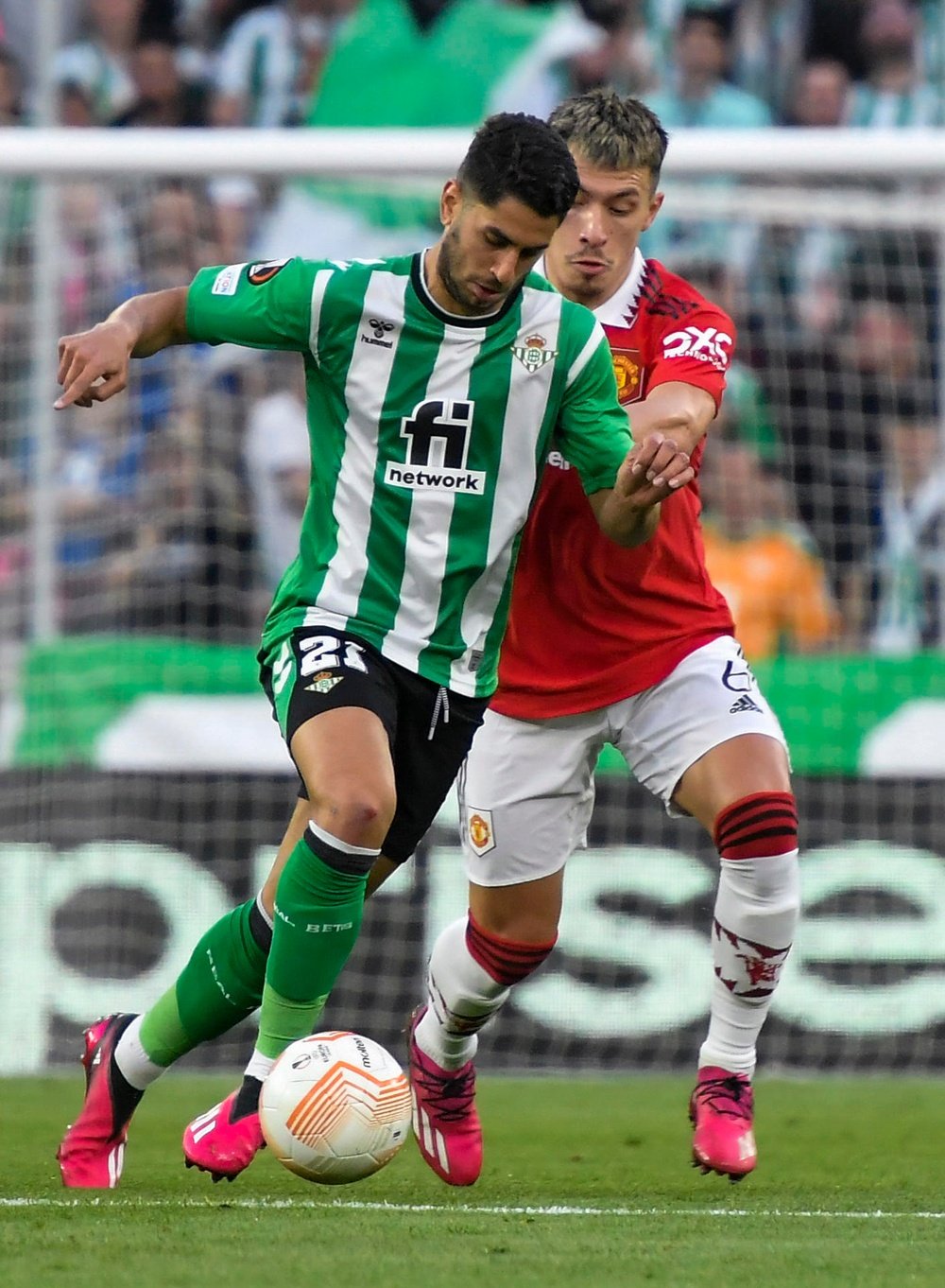 El defensa argentino del Manchester United Lisandro Martínez (d) pelea un balón con el delantero del Betis Ayoze Pérez durante el partido de vuelta de octavos de final de la Liga Europa que ambos equipos disputan hoy jueves en el estadio Benito Villamarín en Sevilla.- EFE / Raúl Caro