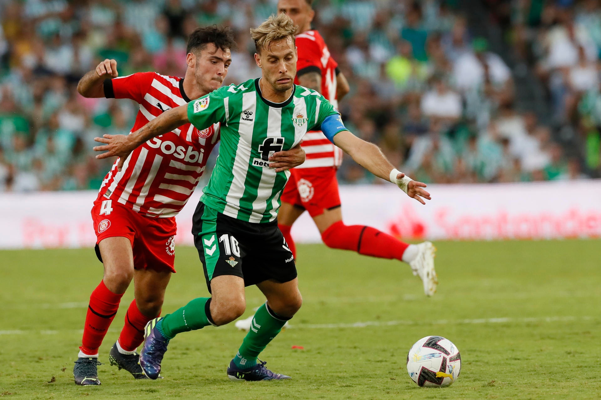 El centrocampista del Betis, Sergio Canales (d), intenta llevarse el balón ante el defensa del Girona, Arnau Martínez, en el estadio Benito Villamarín de Sevilla en foto de archivo de José Manuel Vidal. EFE