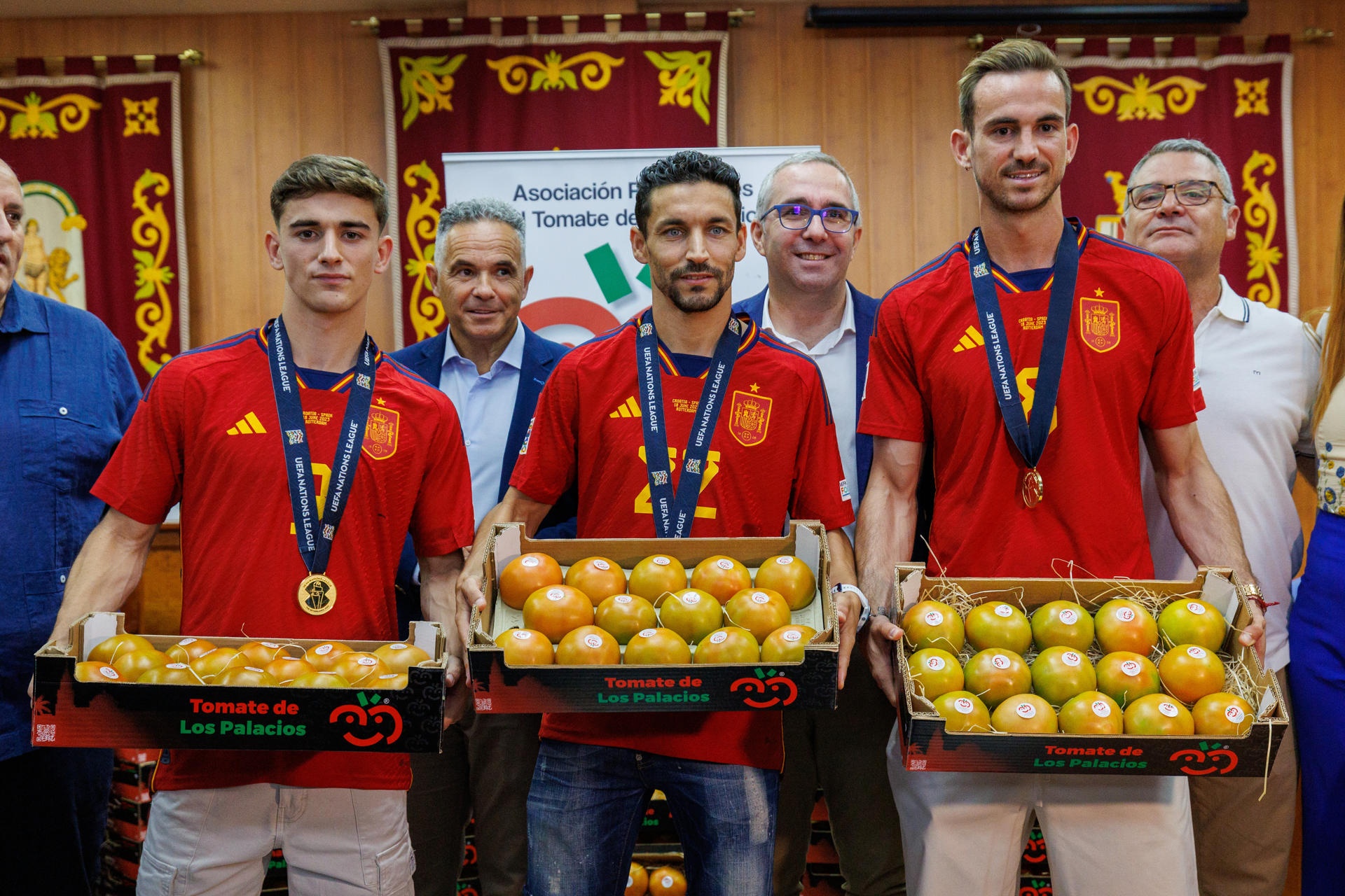 Los futbolistas Jesús Navas (c), Fabián Ruiz (d) y Pablo Páez Gavira `Gavi` (i) reciben su peso en tomates durante el homenaje que su pueblo, Los Palacios y Villafranca (Sevilla), les concede tras la consecución del título de la Liga de Naciones ante Croacia, en un encuentro en el que los tres palaciegos fueron titulares en el once del seleccionador Luis de la Fuente. EFE/ Julio Muñoz