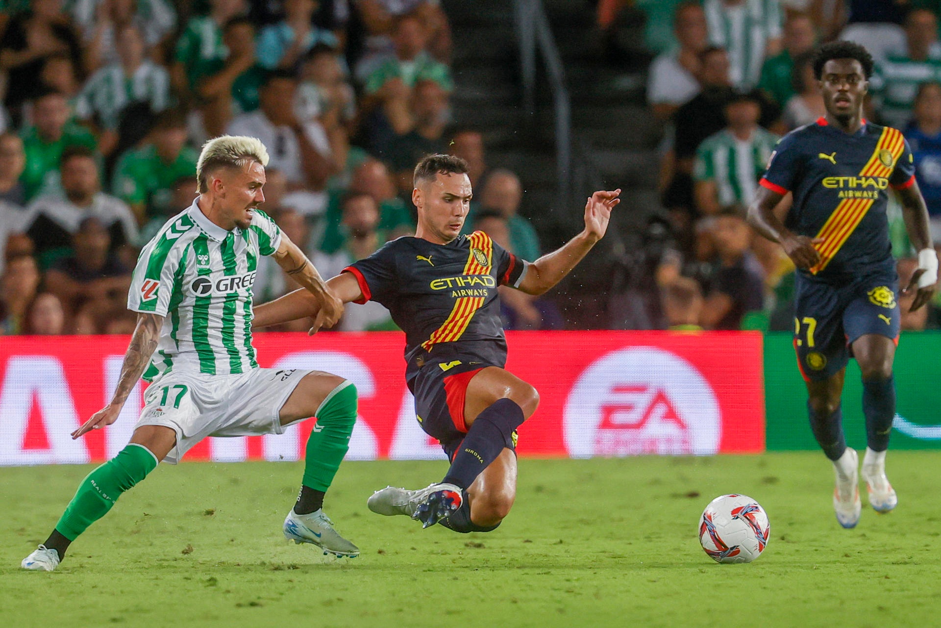 El centrocampista del Betis Rodri (i) lucha con Arnau Martínez (c), del Girona. EFE/José Manuel Vidal