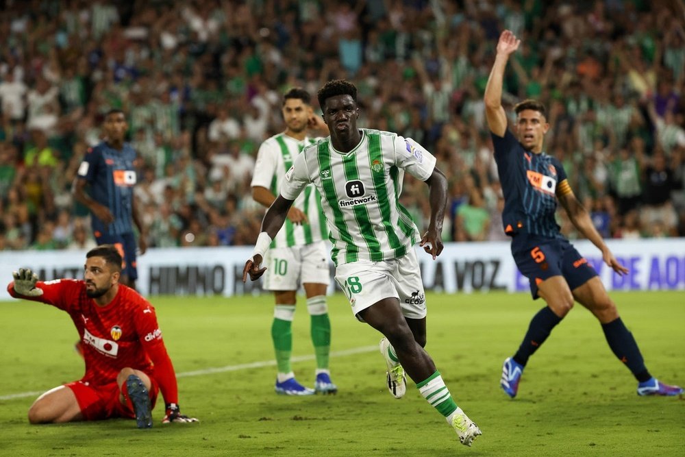 Assane Diao (c), del Betis, tras marcar el 1-0 ante Giorgi Mamardashvili (i) , portero del Valencia. EFE