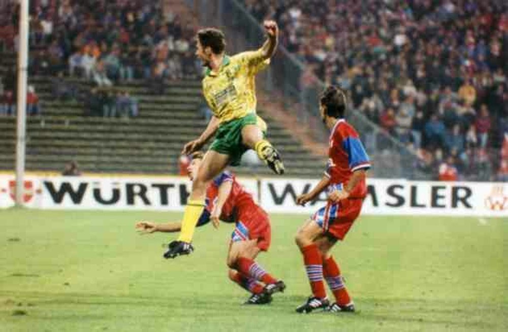 Sutton shoots with two Bayern Munich players looking on back in 1993.