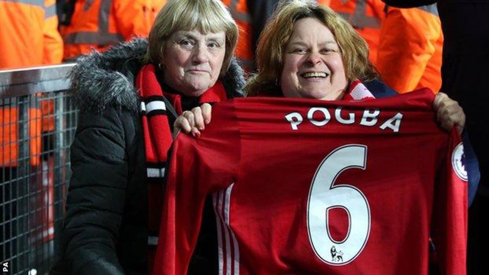 Dos aficionadas muestran la camiseta que Paul Pogba lanzó al público ante el West Brom. BBC