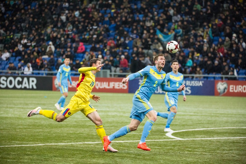 El central kazajo Maliy protege un balón ante el acoso del delantero rumano Stancu, en el Kazajstán-Rumanía de la tercera jornada de las eliminatorias europeas para el Mundial de 2018. FRF