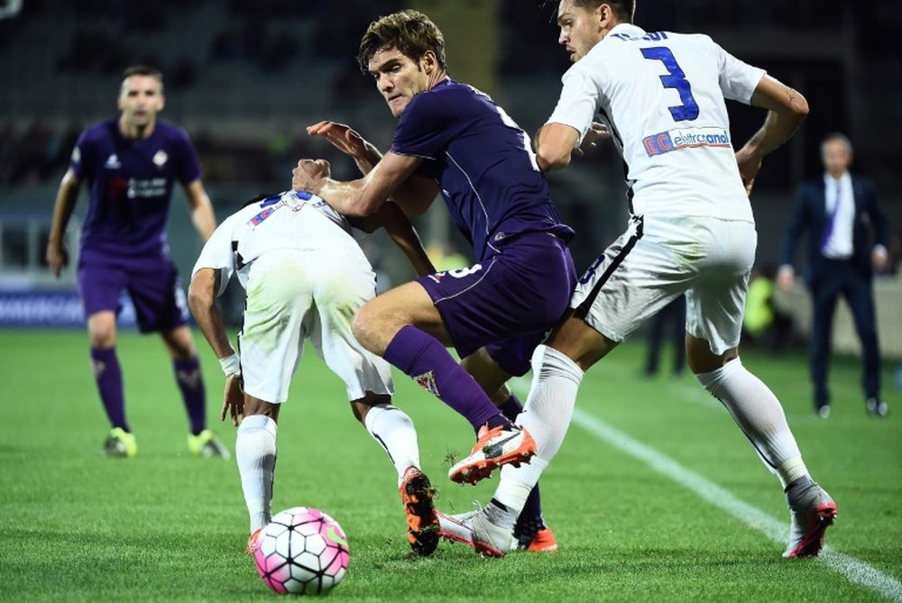 El futbolista de la Fiorentina, Marcos Alonso, pelea por un balón contra varios jugadores del Atalanta. AFP