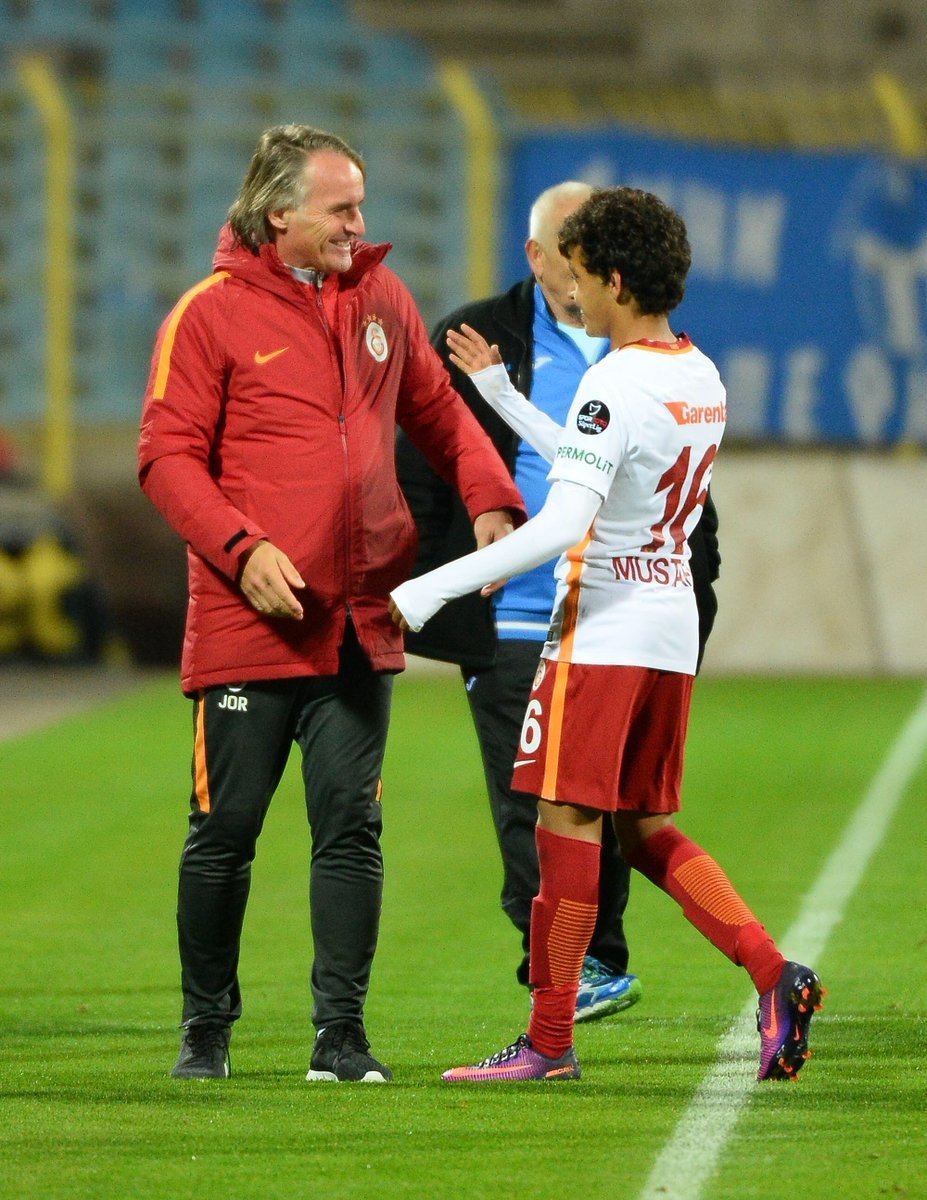 El joven futbolista del Galatasaray Mustafa Kapi recibe la felicitación de su entrenador, Jan Olde Riekerink. Twitter/GalatasaraySK