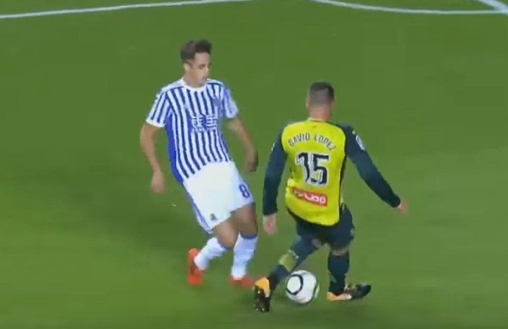 Januzaj le hace un caño a David López antes de dar el pase de gol a Illarramendi. Captura