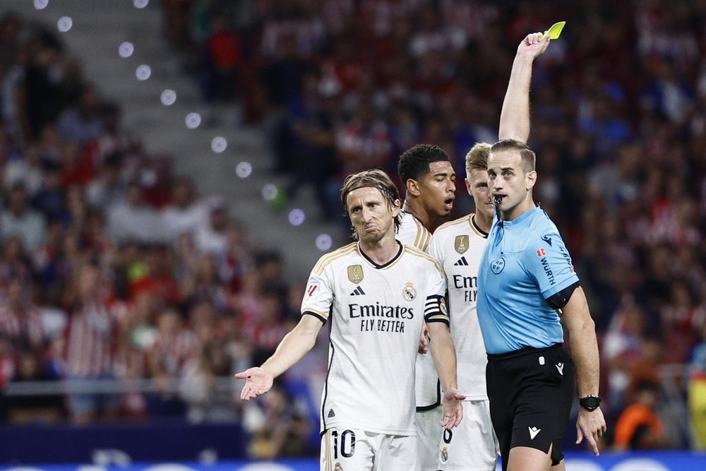 Javier Alberola Rojas (R) enseña una tarjeta amarilla a Luka Modric (L) en el Atlético de Madrid-Real Madrid de Primera División 2023-24. EFE/Rodrigo Jiménez