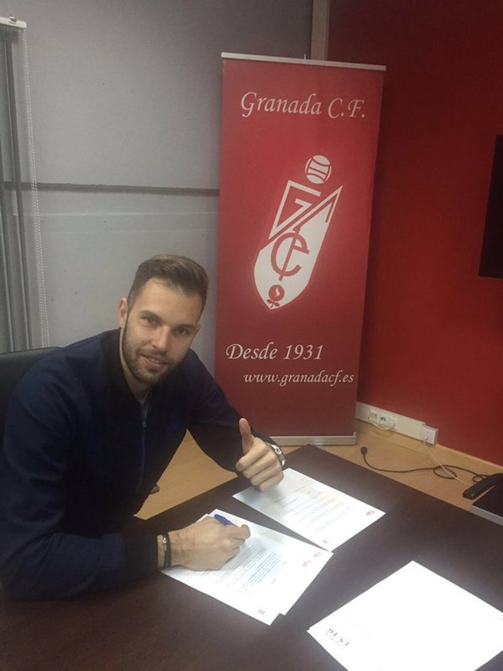Jesús Fernández posa firmando su nuevo contrato con el Granada. Twitter