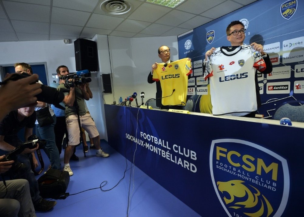 Li Wing-Sang (C), CEO of Hong-Kong based company Ledus, and financial director Chi Hung Chiu (R) show the new jerseys of Sochaux football club on July 6, 2015 during a press conference at the Auguste Bonal stadium in Montbeliard