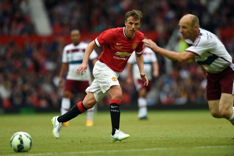 Manchester Utd legend Phil Neville (C) plays the ball during the friendly football match between Manchester United Legends and Bayern Munich All Stars at Old Trafford in Manchester, northwest England, on June 14, 2015.