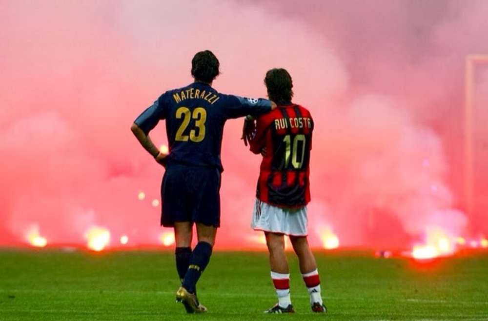 Materazzi y Rui Costa observan las bengalas lanzadas al terreno de juego en un derbi de Milán. AFP