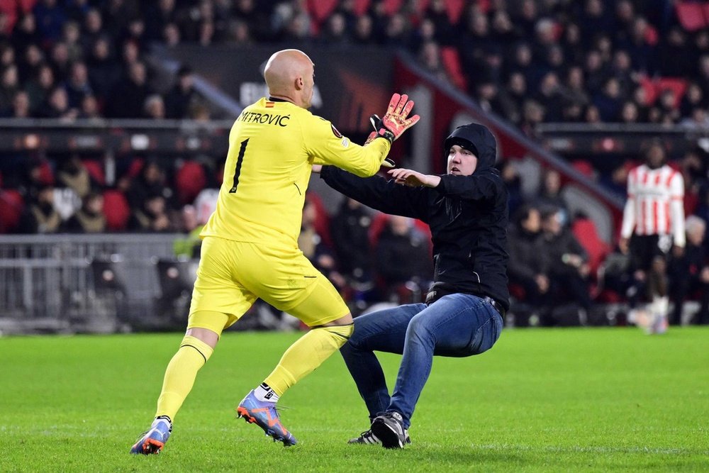 Marko Dmitrovic (L) se dispone a agarrar a un espontáneo en el PSV-Sevilla de Europa League 2022-23. EFE/Olaf Kraak