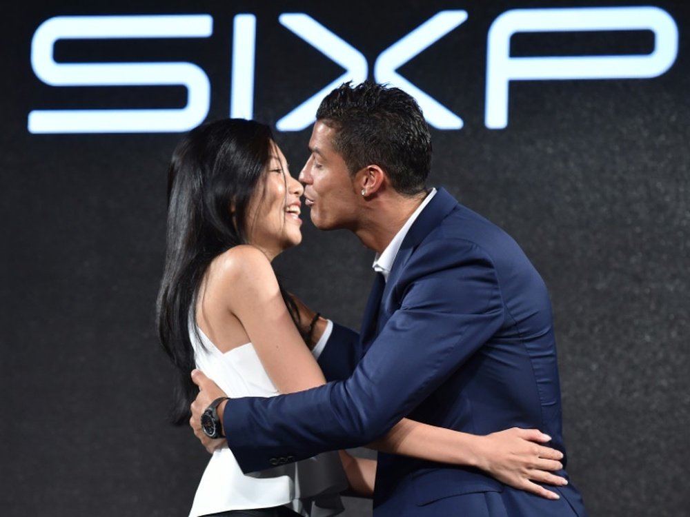 Portuguese footballer Cristiano Ronaldo (R) embraces a fan at a promotional event for an electric muscle stimulation machine during a visit to Tokyo on July 7, 2015