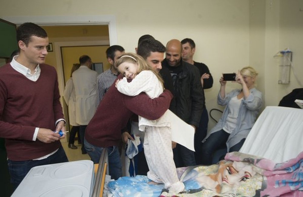 Una pequeña abraza a Juan Domínguez en el hospital ante la mirada de Oriol Riera. Twitter