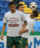El delantero de Australia Tim Cahill (delantero) se calienta con compañeros de equipo mientras usa una camiseta pidiendo a la gente a donar a las víctimas de las inundaciones de Australia antes de 2011 coinciden con grupos de la Copa de Asia de fútbol C e
