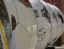 Un hombre asoma por entre la parte gigante de balones de fútbol de una exhibición en Johannesburgo
