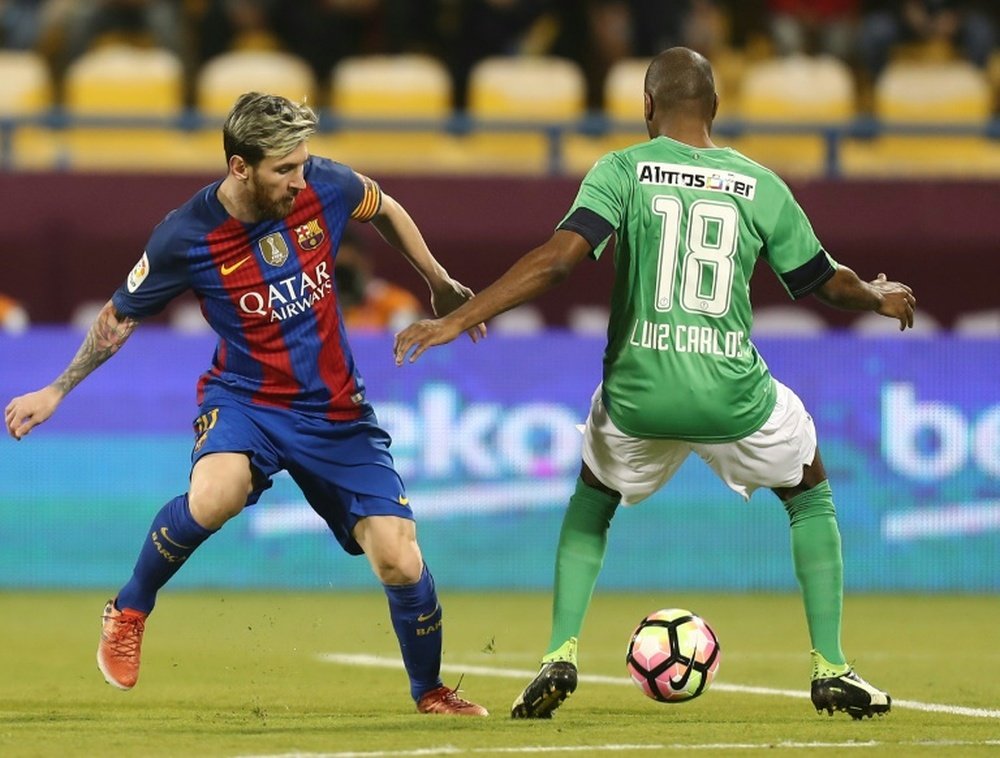 FC Barcelonas Lionel Messi (L) vies with Al-Ahlis Luiz Carlos during a friendly. AFP