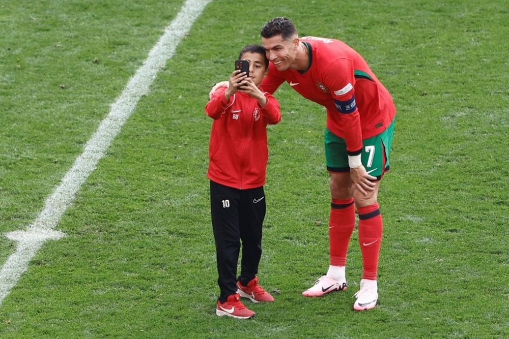 A young pitch invader takes a selfie with Cristiano Ronaldo. AFP