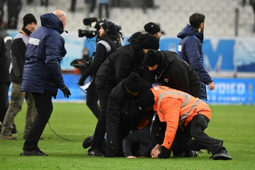 A club at war: Marseille security staff wretsled pitch invaders to the ground at the final whistle
