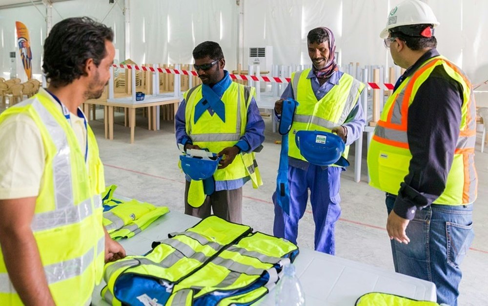 Un technicien échange avec des travailleurs immigrés sur le chantier du stade de Losail à Doha. AFP