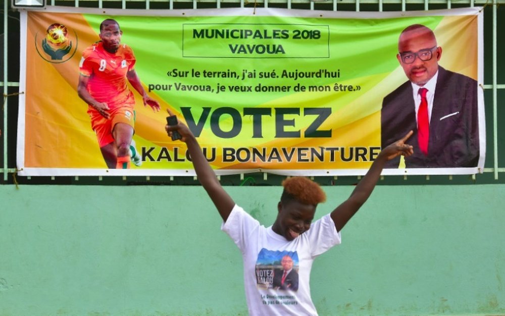 Une Ivoirienne danse devant l'affiche électorale de Bonaventure Kalou. AFP